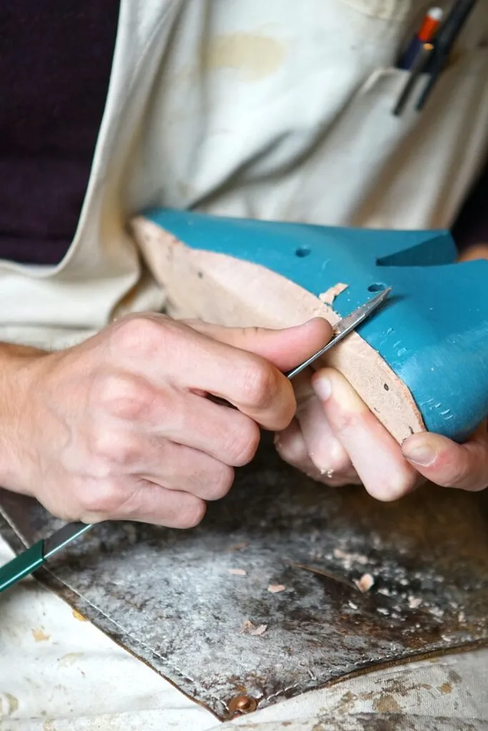 Schuhmacher bearbeitet einen Leisten in Handarbeit