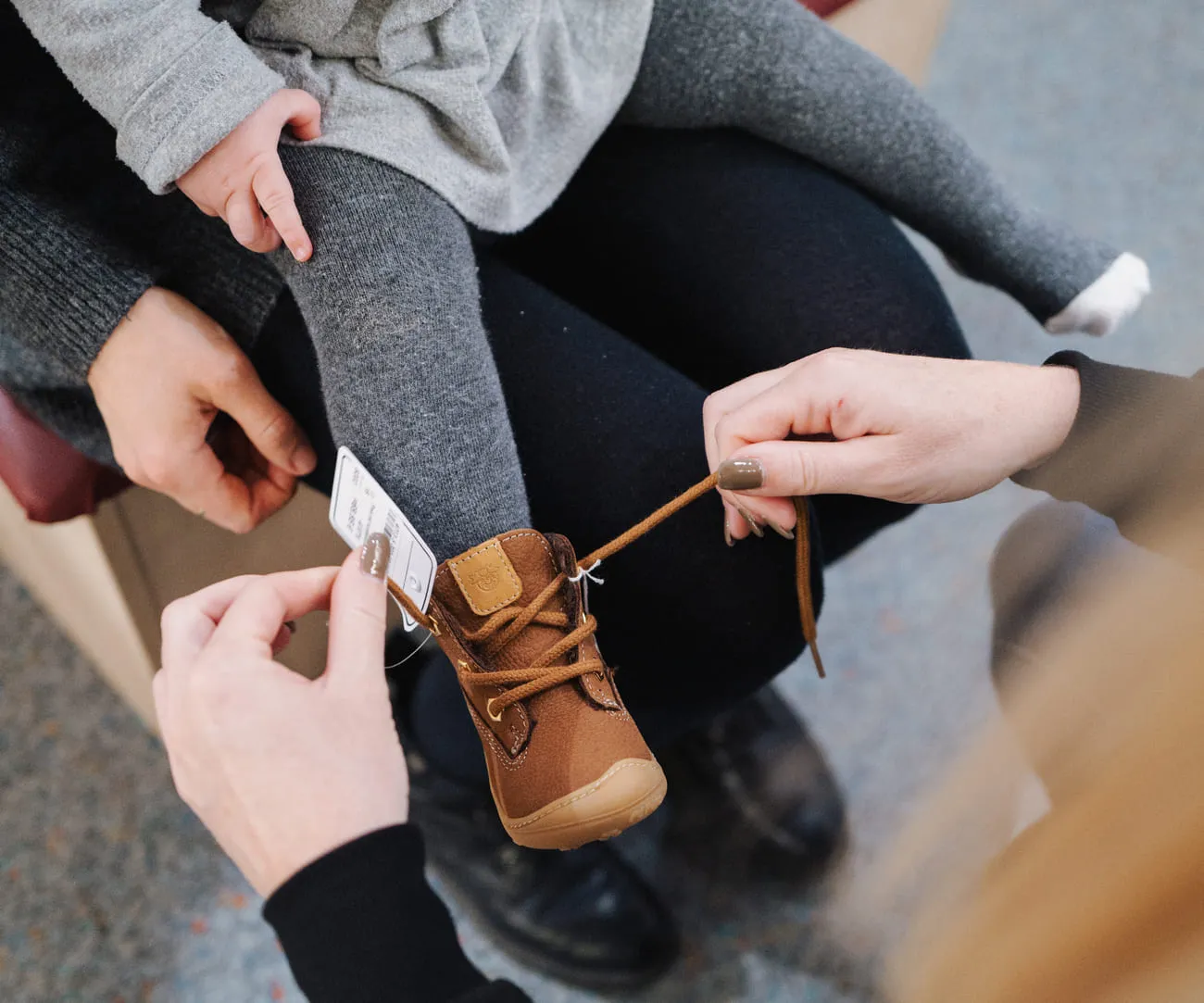 Ein brauner Kinderschuh wird bei der Anprobe geschnürt